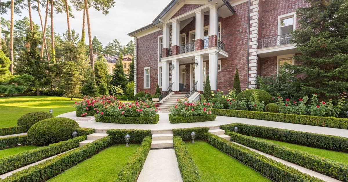 Large brick house with manicured lawn and garden path