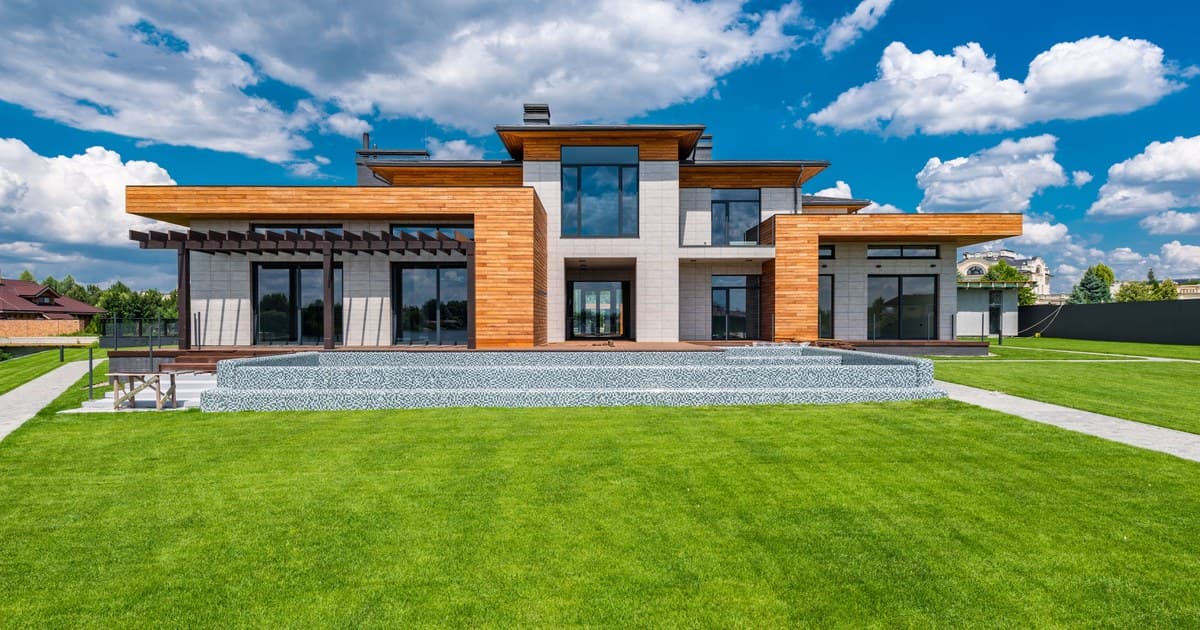 A contemporary mansion with large windows and a landscaped lawn in a developed residential area
