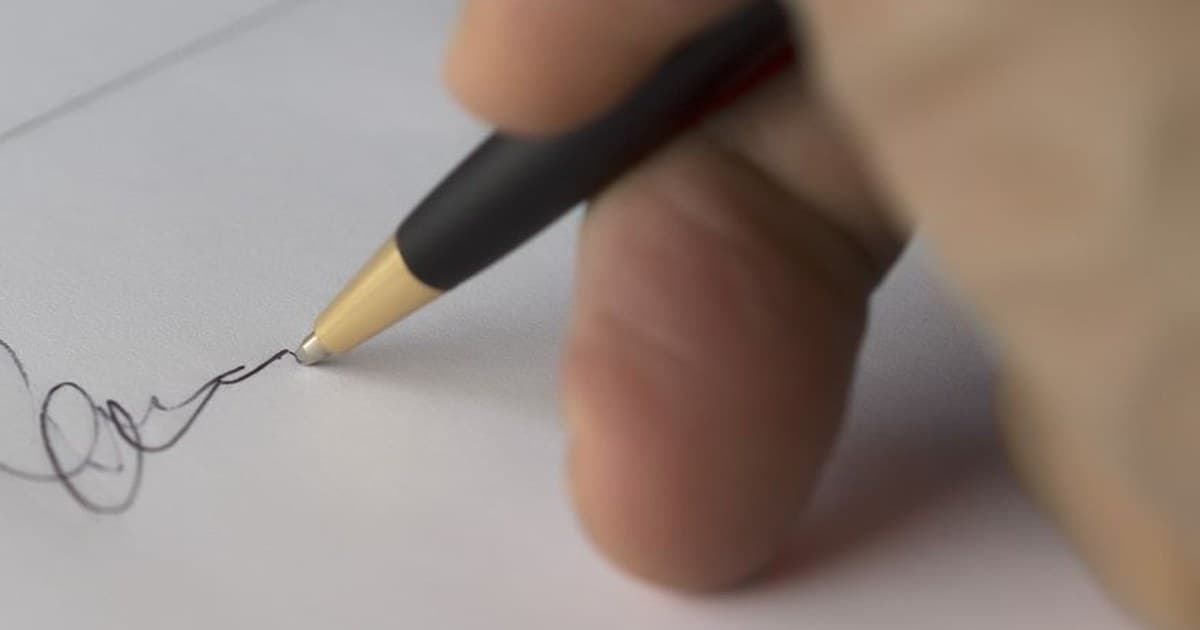 A hand signing a property document with a pen, the step that should only come after the land record has been checked