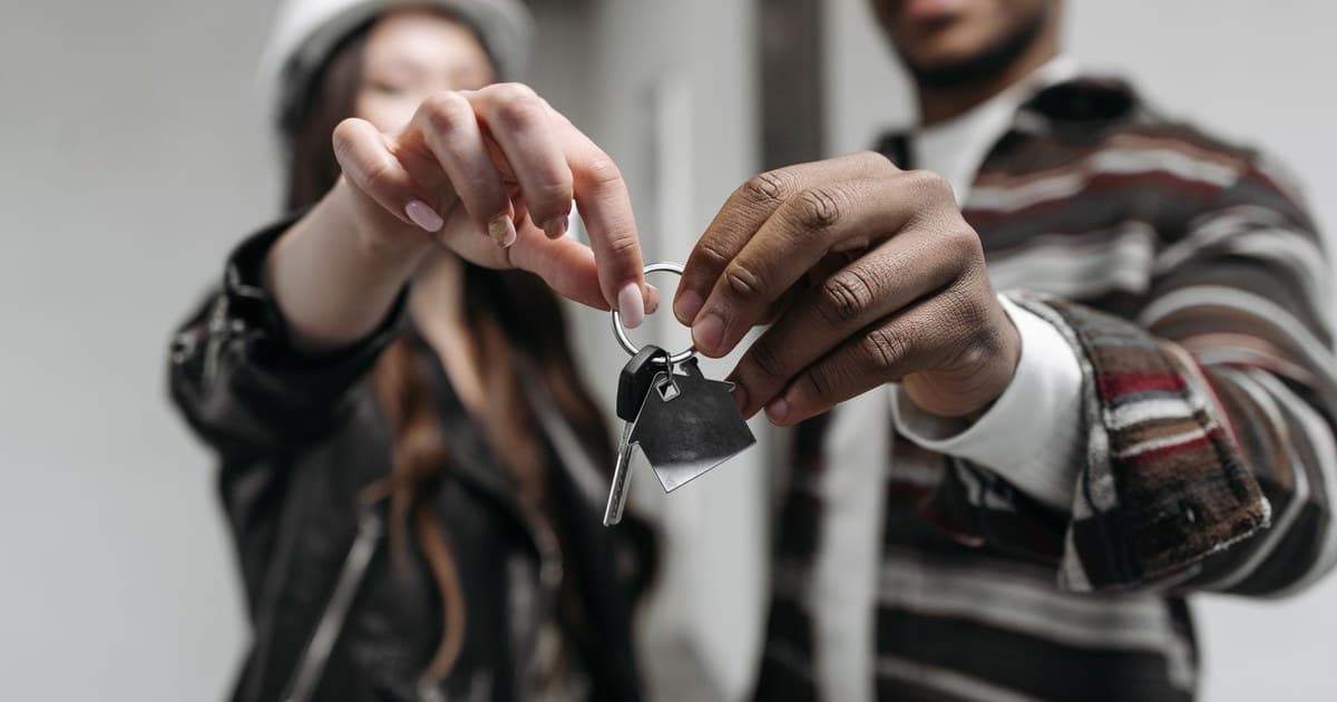 A couple holding the keys to their new home after completing a property purchase