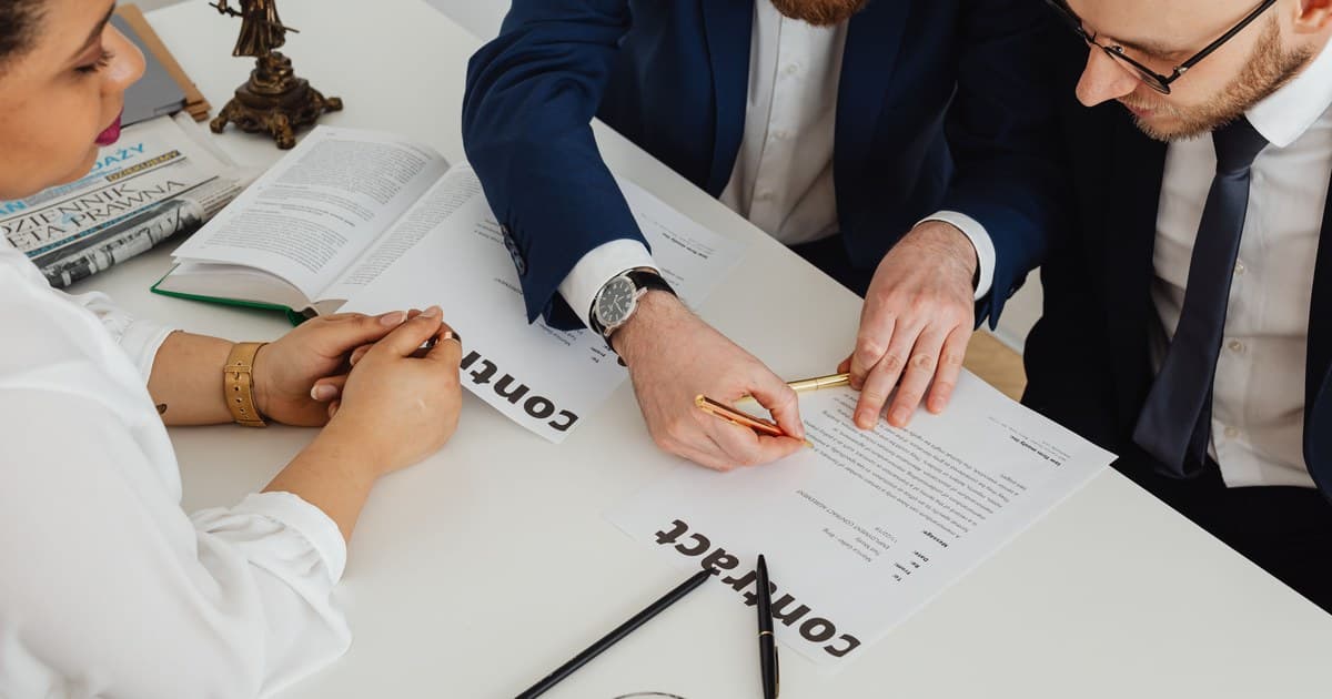 Buyer and agent reviewing signed property contracts and transfer documents on a desk