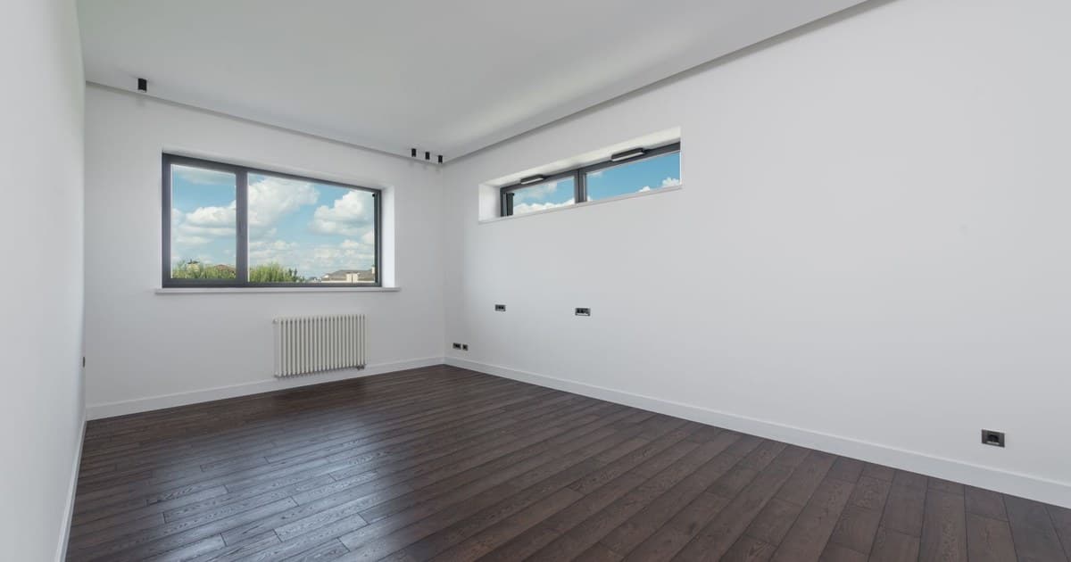 Empty room with dark wooden floor and large windows, ready for a new tenant
